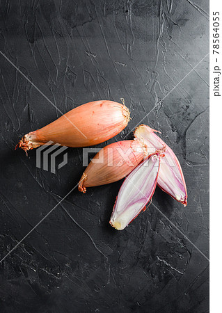 Shallot, eschalot or scallion raw ripe onions sliced and halved black concrete textured background top view close up vertical space for text Shallot, eschalot or scallion raw ripe onions sliced and halved black concrete textured background top view close up vertical space for text 78564055