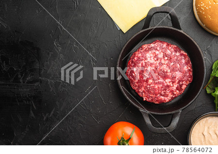 Homemade hamburger. Raw beef patties, sesame buns with other ingredients, on black stone background, top view flat lay, with copy space for text Homemade hamburger. Raw beef patties, sesame buns with other ingredients, on black stone background, top view flat lay, with copy space for text 78564072