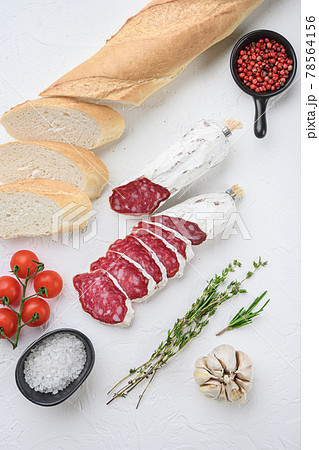Spanish salcichon slices with panini and herbs on white surface, top view Spanish salcichon slices with panini and herbs on white surface, top view 78564156