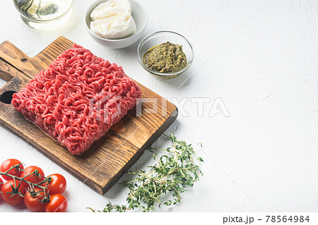 Raw minced meat with spices, vegetables and herbs and meatballs, on white stone background, with copy space for text Raw minced meat with spices, vegetables and herbs and meatballs, on white stone background, with copy space for text 78564984