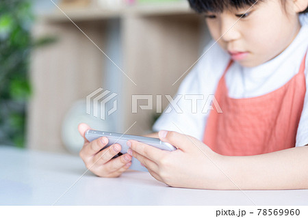 部屋でスマホを使う小学生の女の子の写真素材