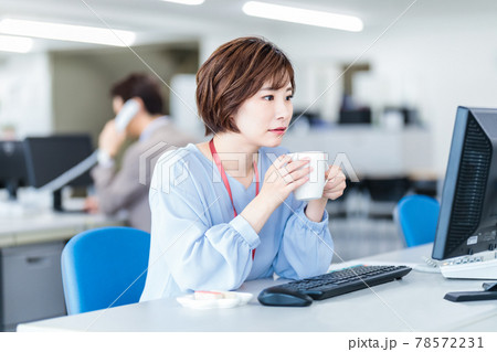 オフィスでコーヒーを飲みながら仕事をする女性 オフィスでコーヒーを飲みながら仕事をする女性 78572231