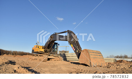 Excavator on earthworks at construction site. Backhoe on foundation work and road construction. Excavator on earthworks at construction site. Backhoe on foundation work and road construction. 78572832