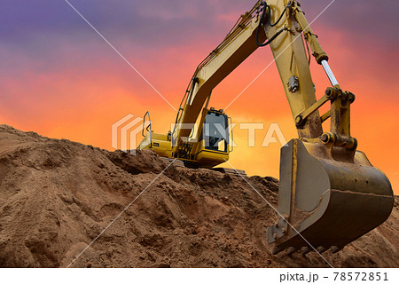 Excavator working on earthmoving at open pit mining on amazing sunset background.  78572851