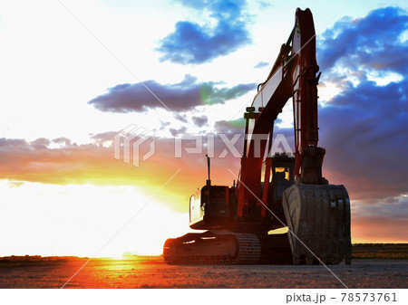 Excavator working on earthmoving at open pit mining on amazing sunset background. Excavator working on earthmoving at open pit mining on amazing sunset background. 78573761