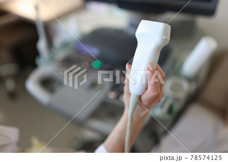 Doctor holding ultrasound probe in his hand in clinic closeup Doctor holding ultrasound probe in his hand in clinic closeup 78574125
