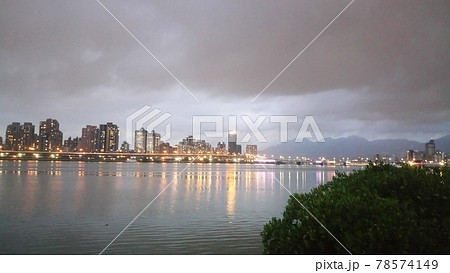 雨雲が垂れ込める中明かりがつき始めた不気味なビル群2 78574149