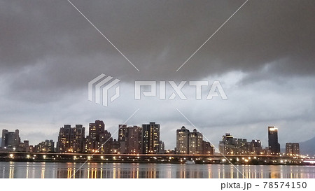 雨雲が垂れ込める中明かりがつき始めた不気味なビル群1 雨雲が垂れ込める中明かりがつき始めた不気味なビル群1 78574150