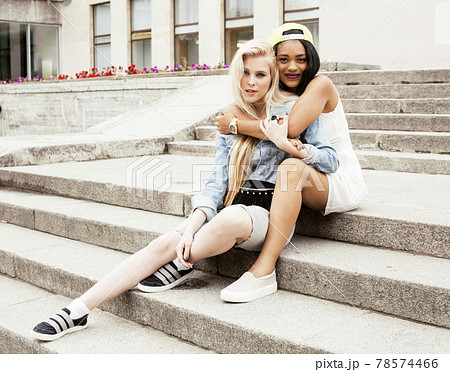 Two teenage girls infront of university building smiling, having fun, lifestyle and people concept Two teenage girls infront of university building smiling, having fun, lifestyle and people concept 78574466