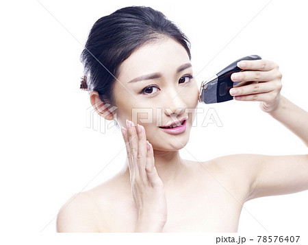 young asian woman using a face spa instrument, isolated on white 78576407
