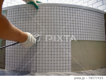Laying ceramic tiles in the bathroom of a residential building. Installing Stone Glass Mosaic Tile Laying ceramic tiles in the bathroom of a residential building. Installing Stone Glass Mosaic Tile 78577435