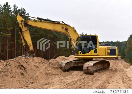 Excavator digs dirt on roadwork during construction dridge in forest area. Heavy machinery Excavator digs dirt on roadwork during construction dridge in forest area. Heavy machinery 78577482