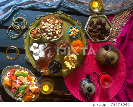 A table with Turkish tea with lale, oriental sweets, rahad delight, a mix of various nuts using copper dishes and bright fabrics. A table with Turkish tea with lale, oriental sweets, rahad delight, a mix of various nuts using copper dishes and bright fabrics. 78578046