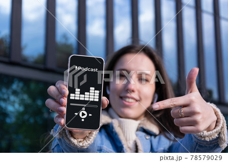 Podcast audio equipment. Audio podcast application on mobile smartphone screen in woman hand. Happy young sexy girl holding recording sound voice equipment background. Live online radio player. Podcast audio equipment. Audio podcast application on mobile smartphone screen in woman hand. Happy young sexy girl holding recording sound voice equipment background. Live online radio player. 78579029