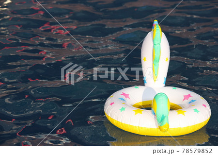 A swimming circle in the form of a unicorn is floating in the pool. 78579852