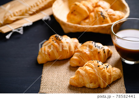 French croissant with black sesame seeds and coffee cup on black background, morning breakfast French croissant with black sesame seeds and coffee cup on black background, morning breakfast 78582441