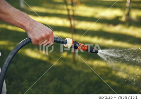 Man watering grass in the garden 78587151