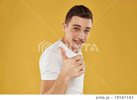 handsome man in white t-shirt gesturing with his hands yellow background 78587183