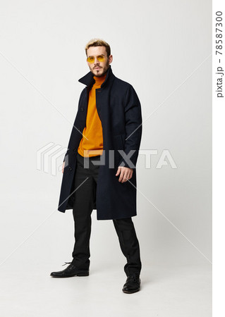 fashion guy in a dark coat and pants boots light background model 78587300
