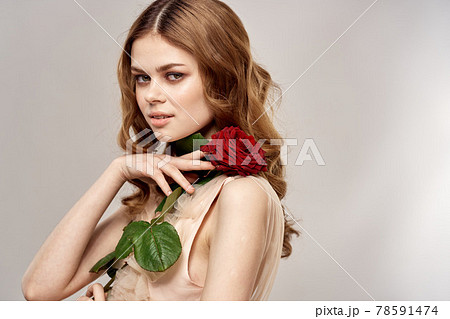 Red-haired woman with a rose in her hands on a light background emotions model portrait close-up Red-haired woman with a rose in her hands on a light background emotions model portrait close-up 78591474