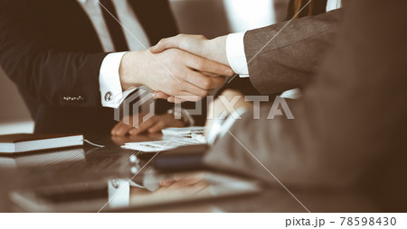 Unknown businessman shaking hands with his colleague or partner above the glass desk in modern office, close-up. Business people group at meeting Unknown businessman shaking hands with his colleague or partner above the glass desk in modern office, close-up. Business people group at meeting 78598430