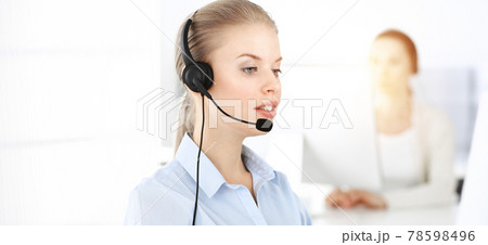 Blond woman working in sunny call center. Group of diverse people working as customer service occupation. Business concept Blond woman working in sunny call center. Group of diverse people working as customer service occupation. Business concept 78598496