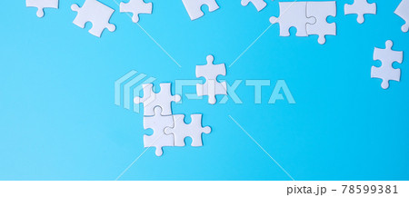 Group of white puzzle jigsaw pieces on blue background. Concept of solutions, mission, success, goals, cooperation, partnership, strategy and puzzle day 78599381