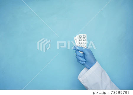 doctor hand holding blister pack against blue background  78599792