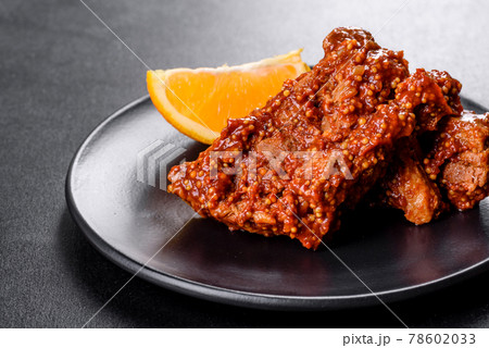 Delicious fresh baked pork ribs with orange on a black plate 78602033