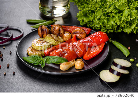 Tasty fresh vegetables grill: tomatoes, peppers, mushrooms, zucchini and onions on a black plate Tasty fresh vegetables grill: tomatoes, peppers, mushrooms, zucchini and onions on a black plate 78602040
