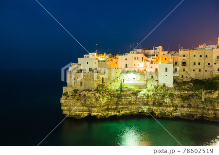 イタリア　ポリニャーノ・ア・マーレ　夜のカラ・ポルト海岸と断崖の上の町並み	 78602519
