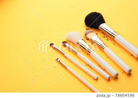 Makeup brushes in different sizes on a yellow background and glitter cropped look Makeup brushes in different sizes on a yellow background and glitter cropped look 78604596