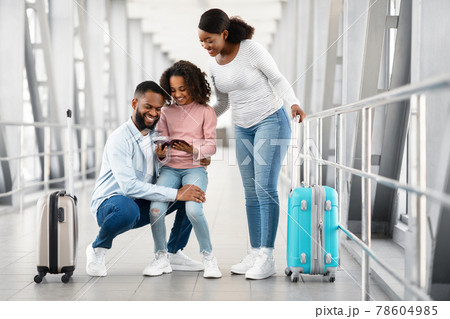 Happy excited black family traveling, looking at documents in airport 78604985
