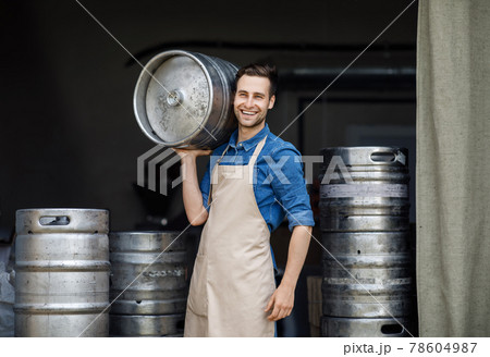 Attractive confident strong man working at plant. Owner of brewery, employee at storage Attractive confident strong man working at plant. Owner of brewery, employee at storage 78604987