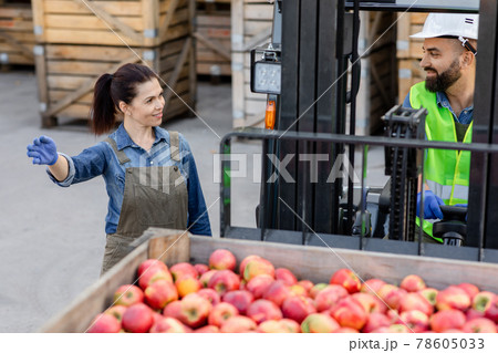 Forklift loading truck with container full of red apples. Fruits and food distribution to market Forklift loading truck with container full of red apples. Fruits and food distribution to market 78605033