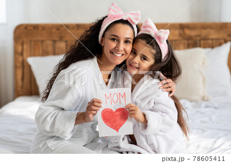 Happy young woman with gift card hugging her child Happy young woman with gift card hugging her child 78605411