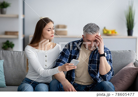Mature woman confronting her husband about correspondence with his lover on smartphone Mature woman confronting her husband about correspondence with his lover on smartphone 78605477