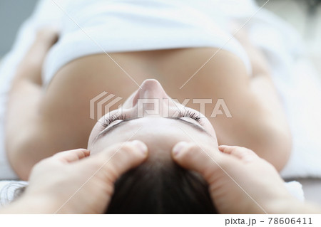 Young woman masseur makes face and head massage in spa salon 78606411