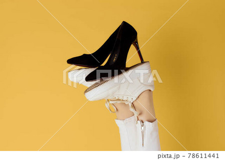 Female feet in sneakers black fashion shoes yellow background 78611441