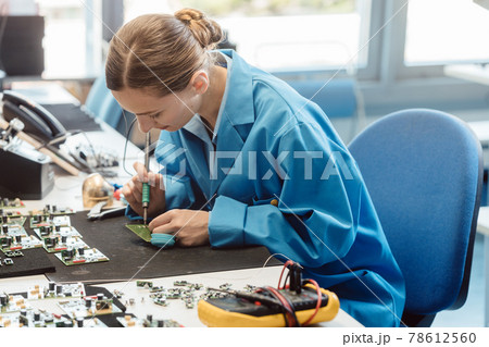 Worker in electronics manufacturing soldering a component 78612560