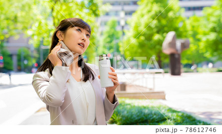 外で汗を拭きながら水分補給をするビジネスウーマン 外で汗を拭きながら水分補給をするビジネスウーマン 78612746