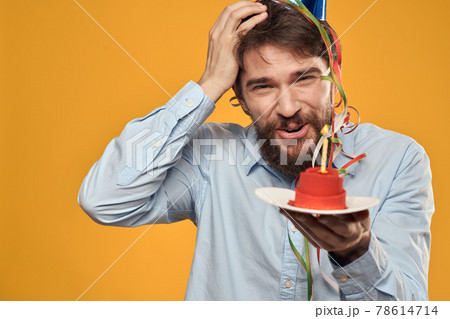 Birthday boy in a cap with a birthday cake in his hand and a candle 78614714