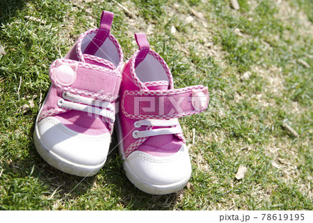 芝生の上にピンク色の子供の靴があります。 78619195