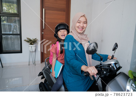 muslim mother taking her daughter to school by motorcycle in the morning 78623723