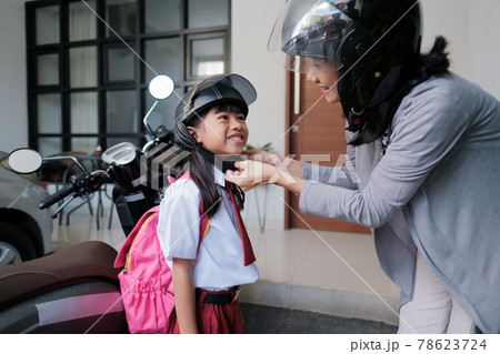 asian mother fasten her daughter helmet before going to school asian mother fasten her daughter helmet before going to school 78623724
