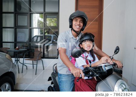 father taking his daughter to school by motorcycle in the morning father taking his daughter to school by motorcycle in the morning 78623824