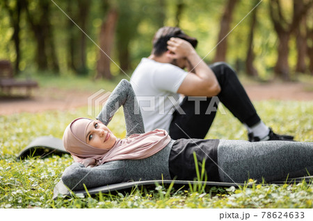 Muslim couple lying on yoga mat and doing abs exercises 78624633