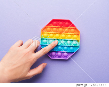 Pop it fidget toys to reduce stress and anxiety in kids and adults, hand pushing a bubble 78625438