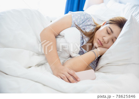 women sleeping in cozy white bed, Asian chubby young fat girl rest with cellphone. 78625846