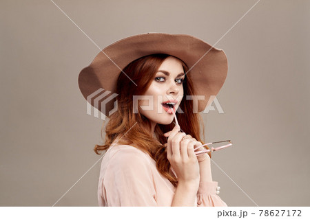 red-haired woman in hat and shirt on beige background makeup smile charm youth fashion 78627172